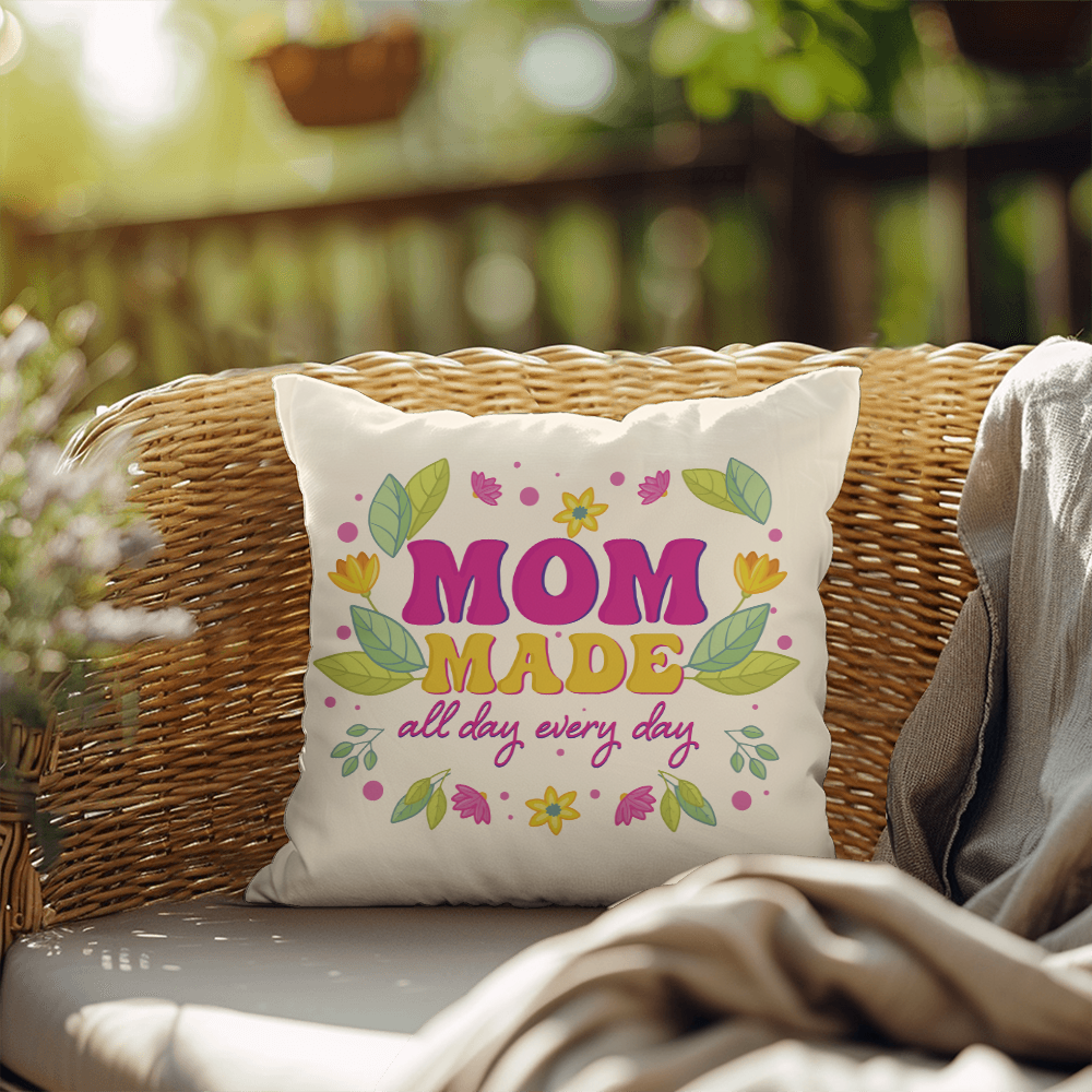 IndoorOutdoor Pillow with "Mom Made All Day Every Day" design on a wicker chair outdoors.