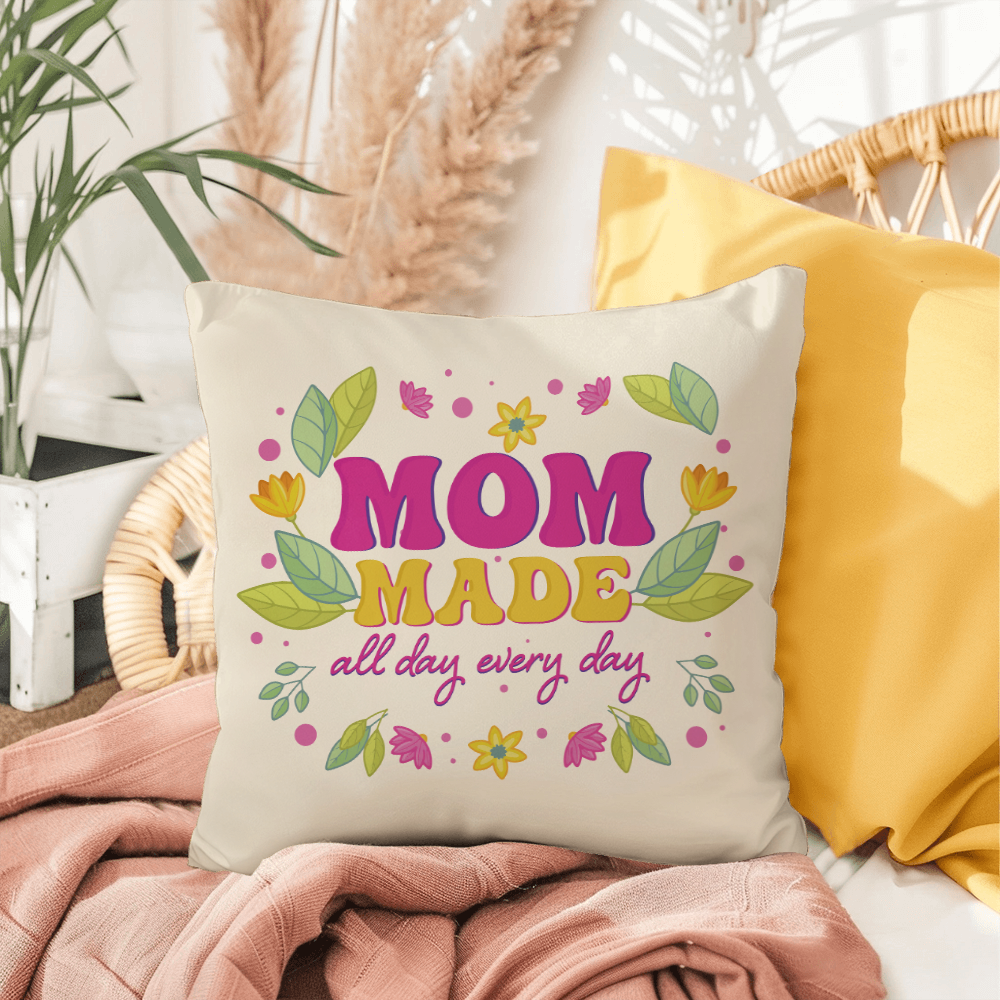 Indoor outdoor pillow with "Mom Made All Day Every Day" print, polyester material, surrounded by cozy decor.