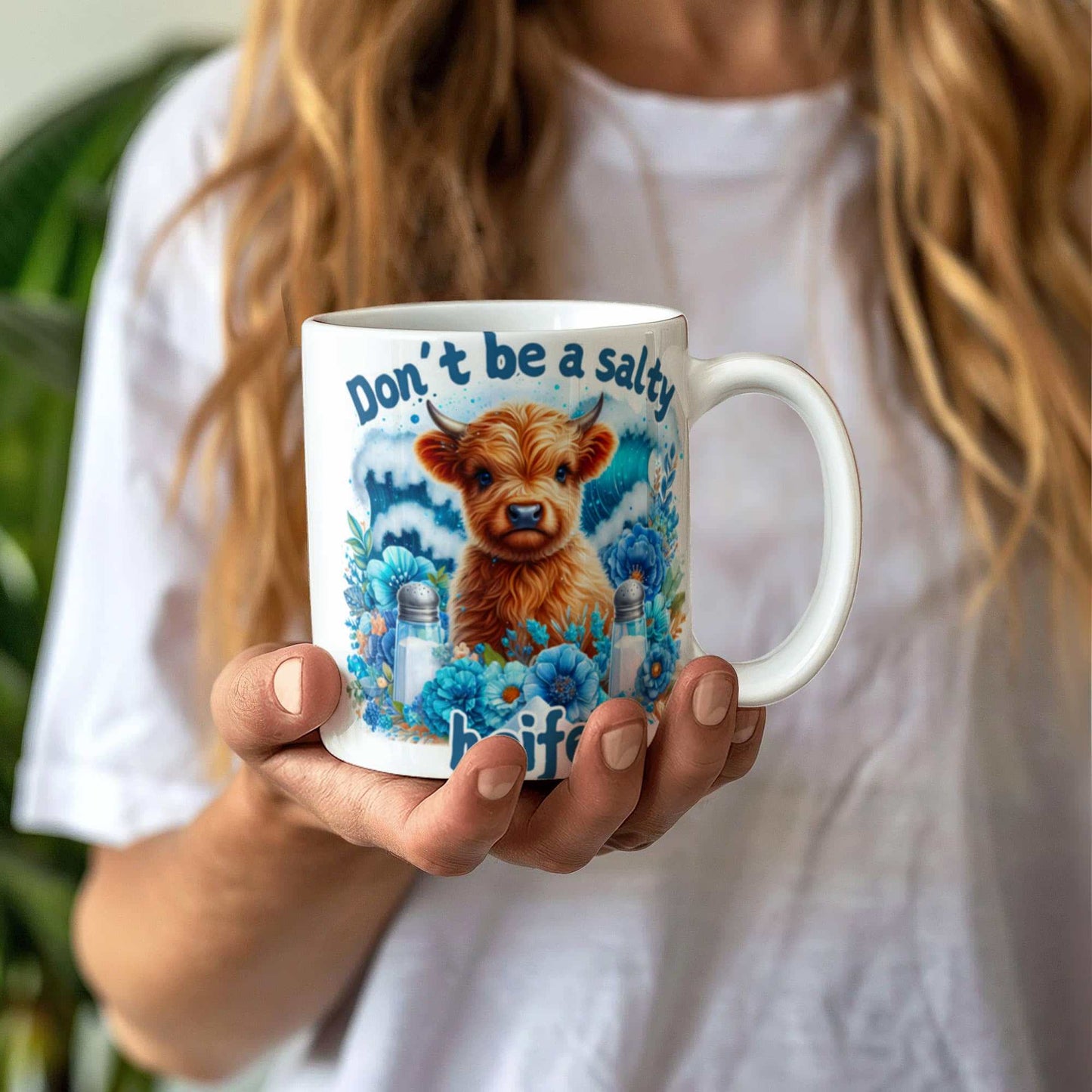 humorous coffee mug with cow design and text "Don't be a salty heifer," held in hand, ceramic, dishwasher and microwave safe