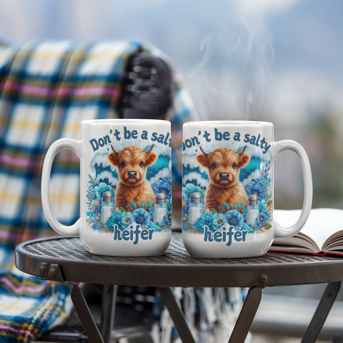 Humorous coffee mug with "Don't be a salty heifer" design on patio table.