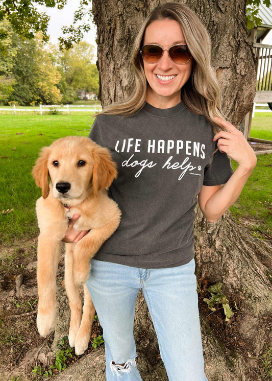 Comfort Wash Graphic Tee with "Life Happens Dogs Help" design, worn by woman holding a puppy.