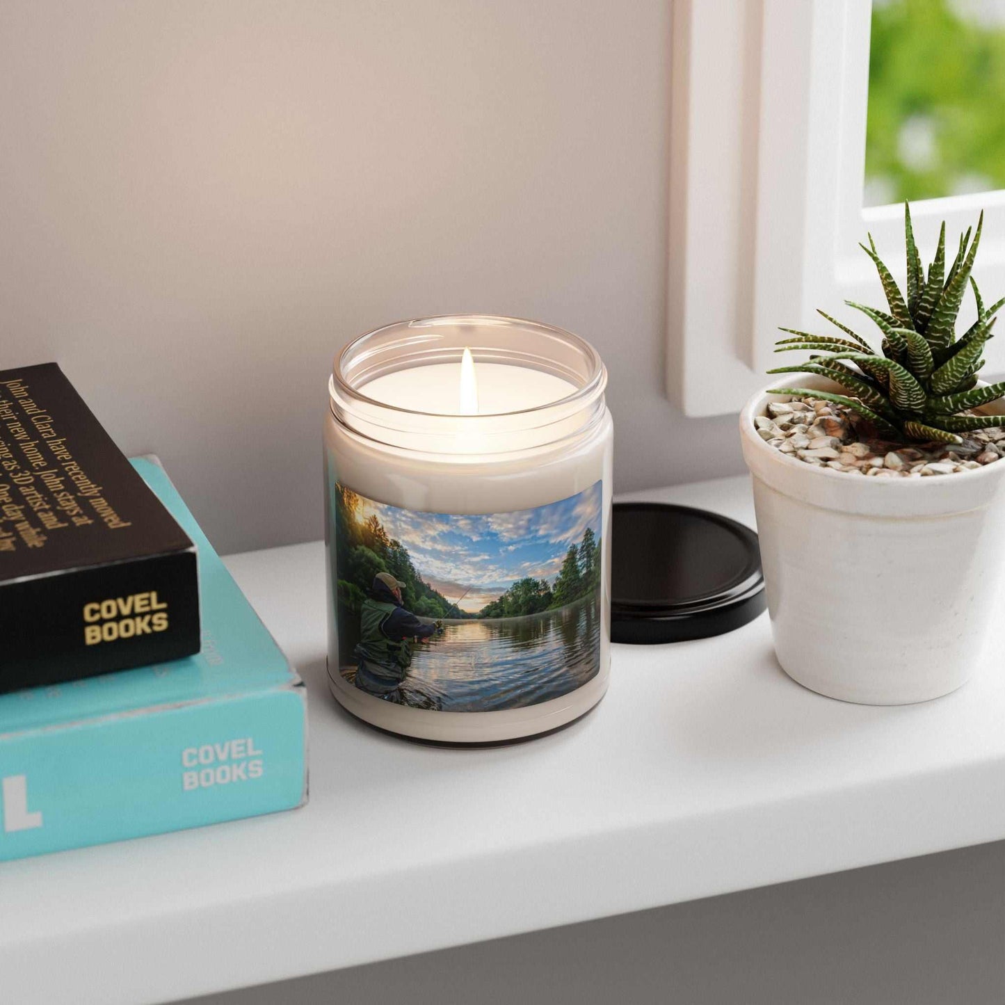 Scented soy candle 9 oz in a glass jar with custom label, beside a plant and books.