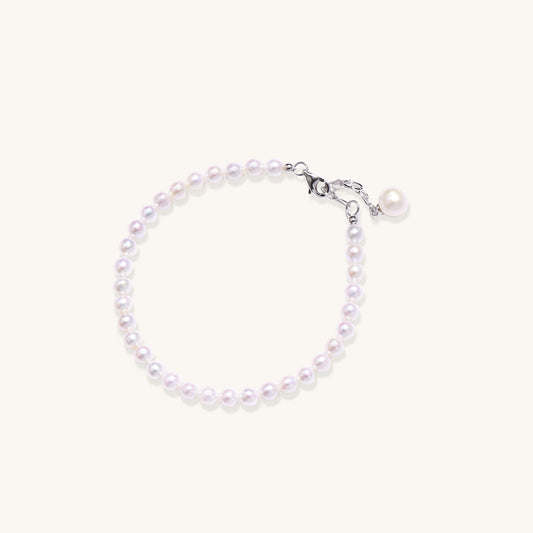 Delicate sterling silver bracelet with small freshwater pearls and adjustable chain on neutral background.