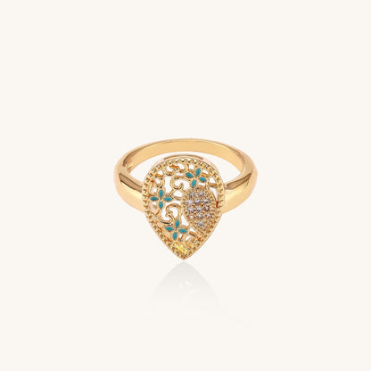 Gold-plated heart ring with turquoise enamel scrollwork and cubic zirconia stones on white background