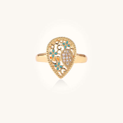 Gold-plated heart ring with turquoise enamel scrollwork and cubic zirconia stones on white background