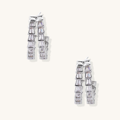 Gold-plated huggie hoops featuring vertical rows of clear baguette zirconia stones in geometric linear design