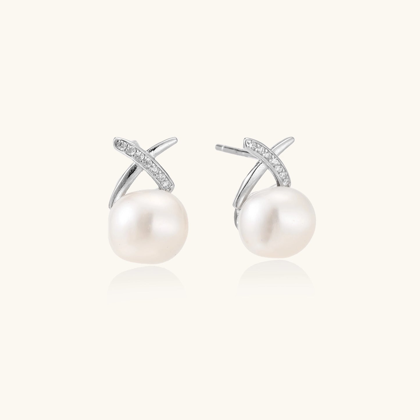 Sterling silver cross-shaped stud earrings with round freshwater pearls dangling below on white background.