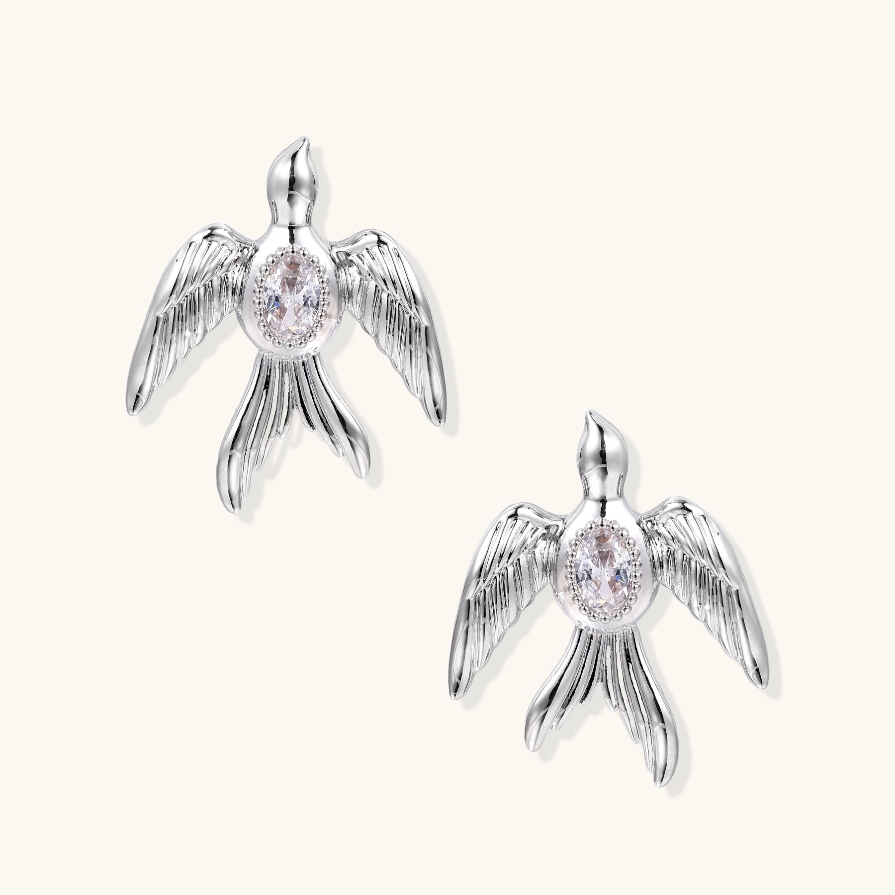 Gold-plated angel wing stud earrings with detailed feather texture and oval zirconia stones in centers