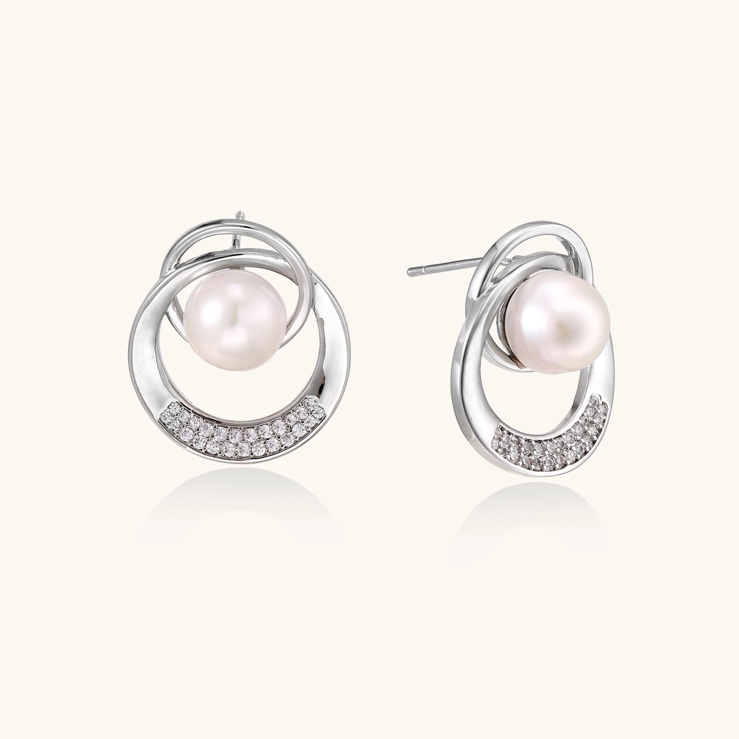Gold-plated brass stud earrings with swirled circular design holding white freshwater pearls and small crystals