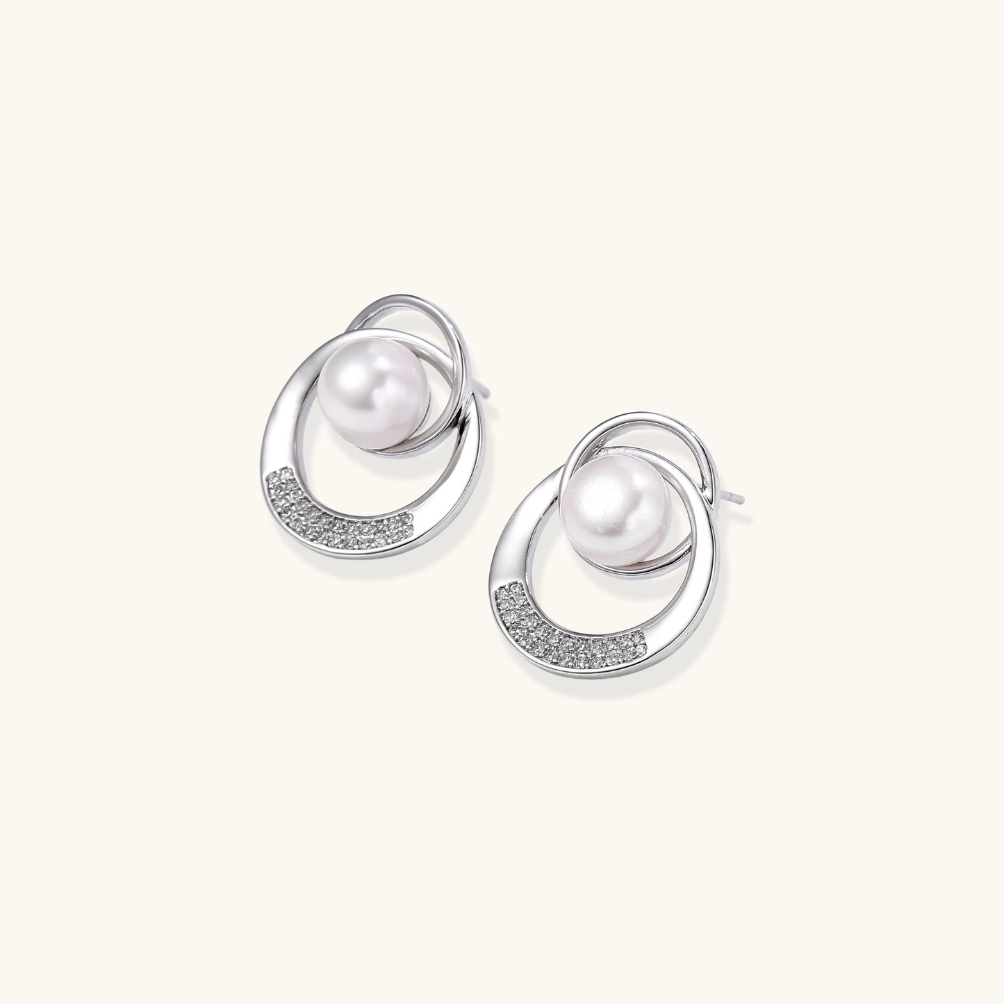 Gold-plated brass stud earrings with swirled circular design holding white freshwater pearls and small crystals