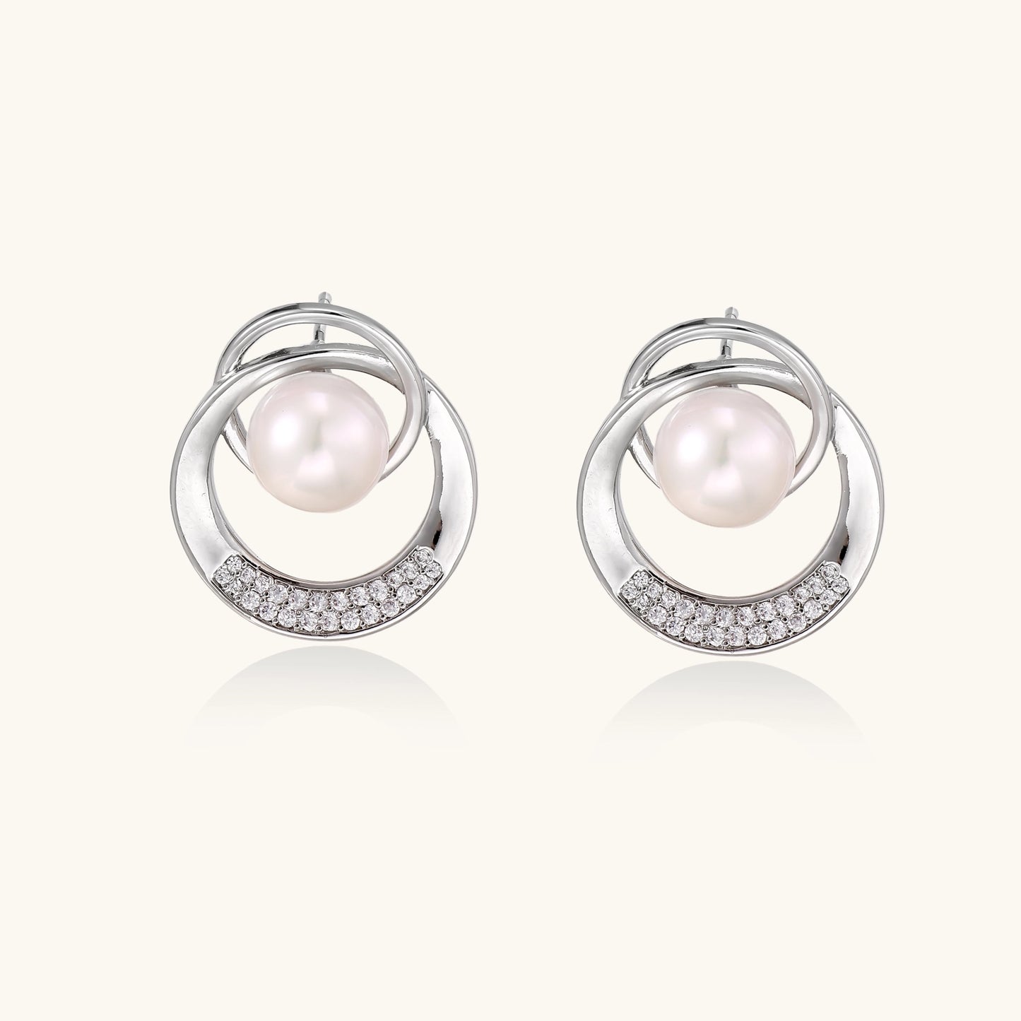 Gold-plated brass stud earrings with swirled circular design holding white freshwater pearls and small crystals