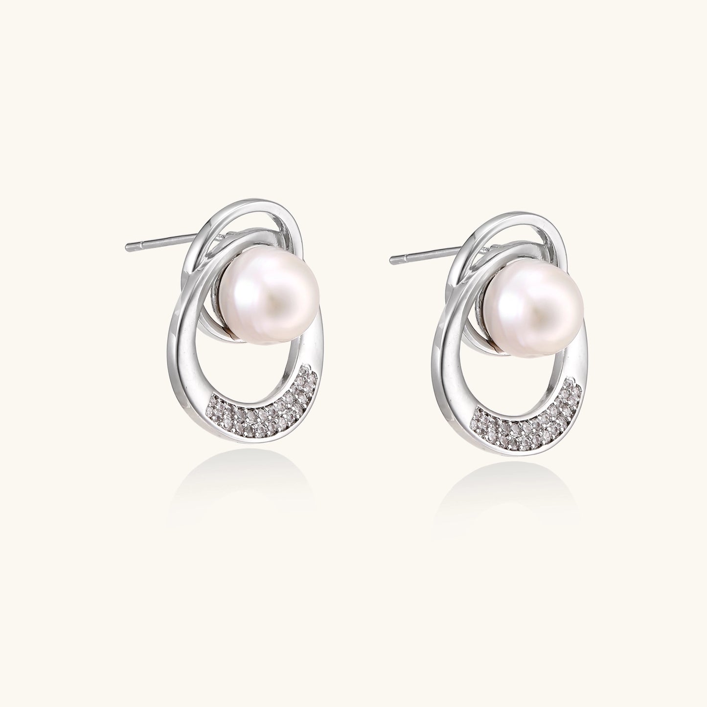 Gold-plated brass stud earrings with swirled circular design holding white freshwater pearls and small crystals