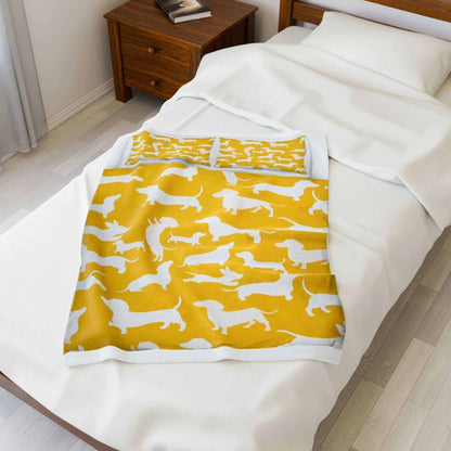 Velveteen plush blanket with yellow dachshund pattern on a bed for dog lovers.