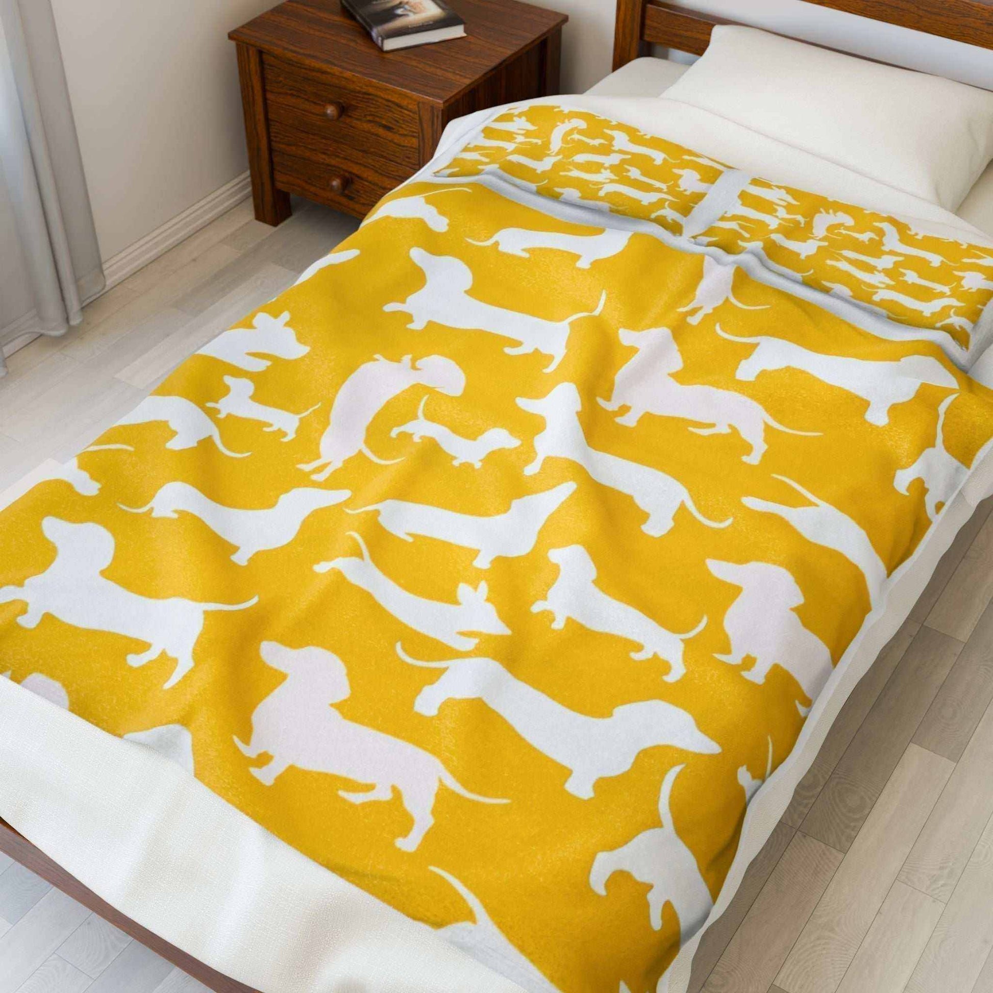 Velveteen plush blanket with dachshund print pattern for dog lovers, displayed on a bed.