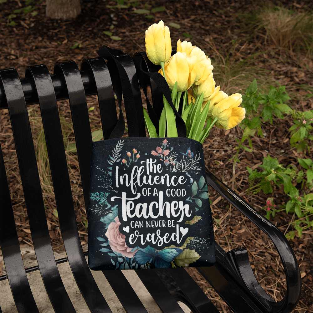 Classic tote bag with inspiring teacher quote and floral design on a park bench.
