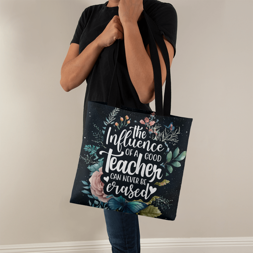 Classic tote bag with floral design and "The Influence of a Teacher Can Never Be Erased" quote, polyester fabric.