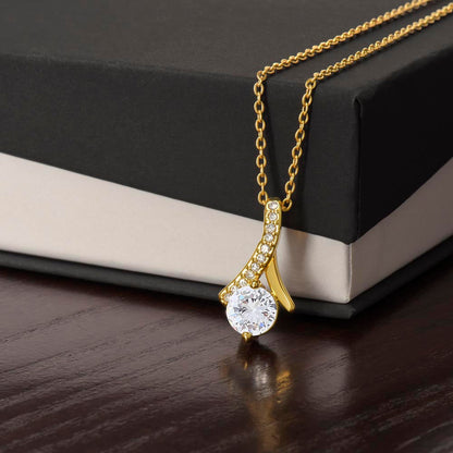 Elegant alluring necklace with gold finish and cubic zirconia pendant on gift box.