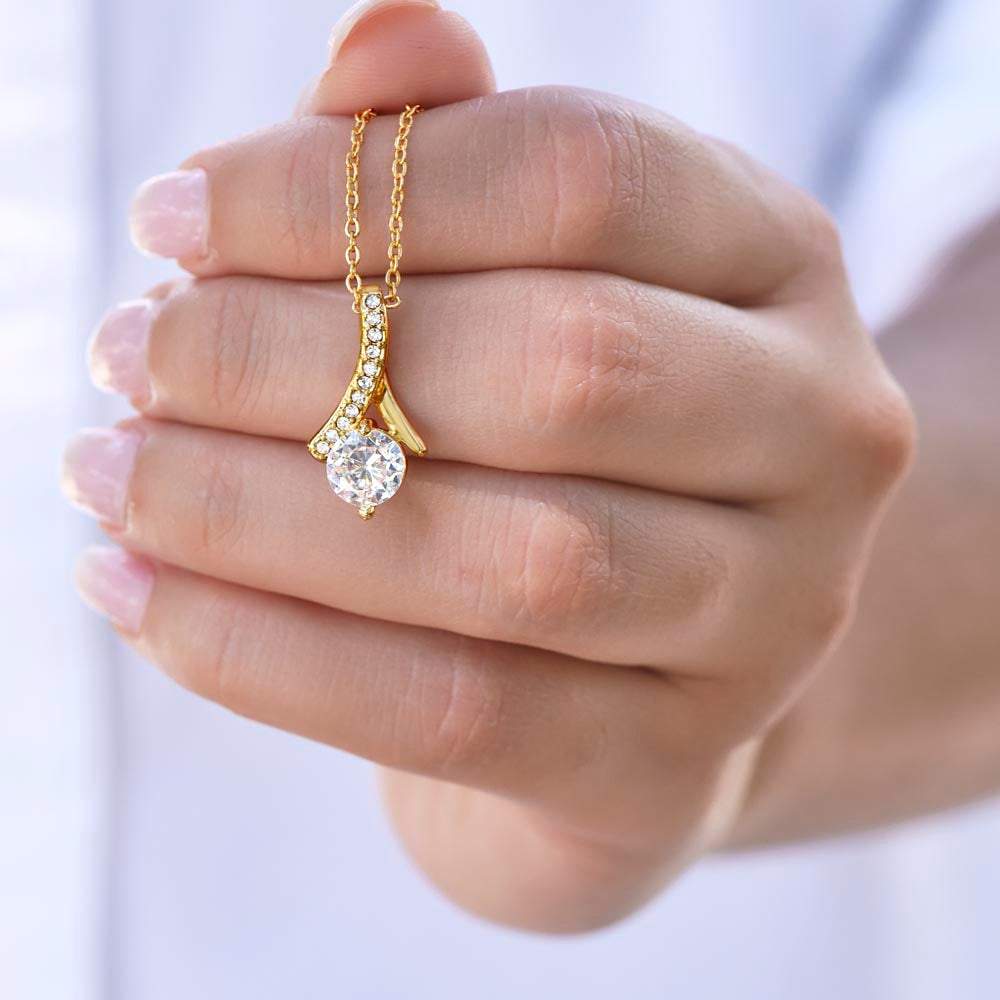 Alluring necklace with gold ribbon-shaped pendant and cubic zirconia.